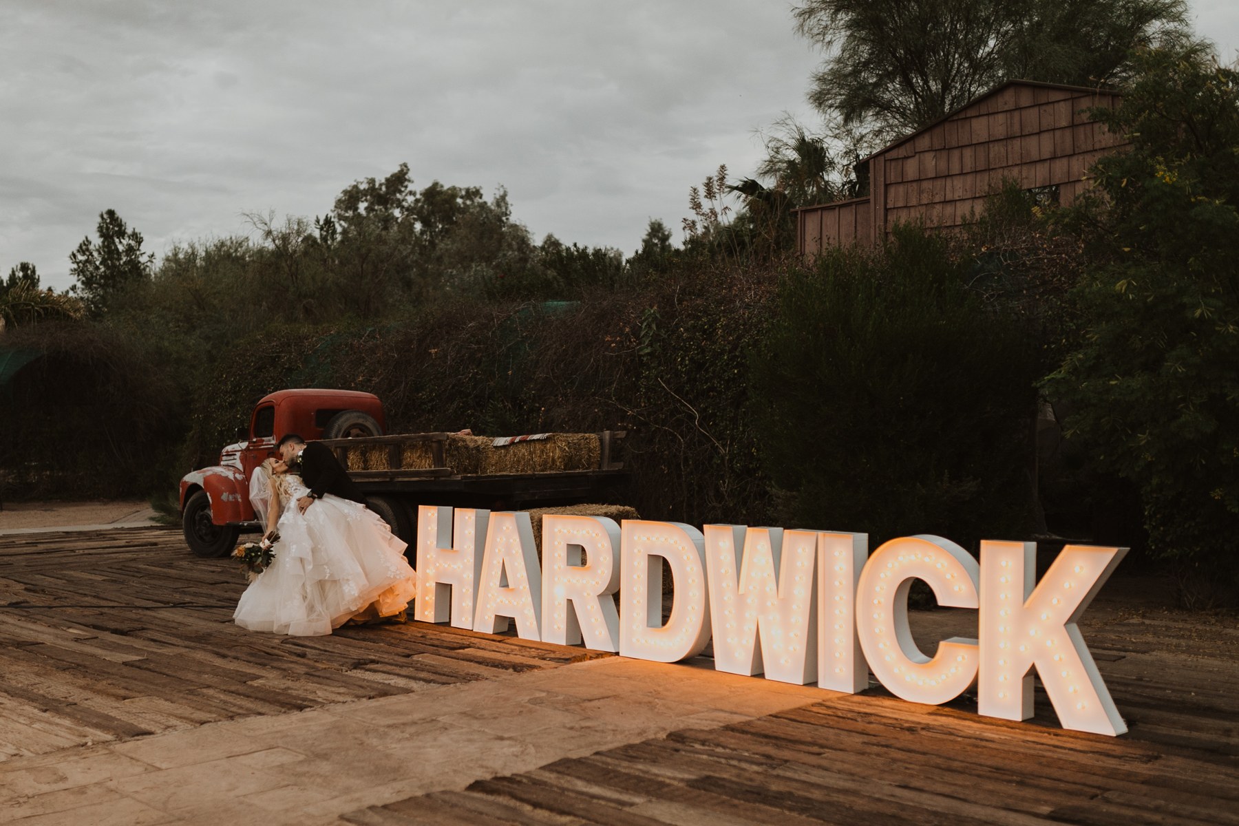 Patrick and his bride beside glowing HARDWICK marquee letters at their wedding
